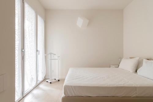 una camera bianca con letto bianco e ampie finestre di LUVI - Flavio Gioia a Milano