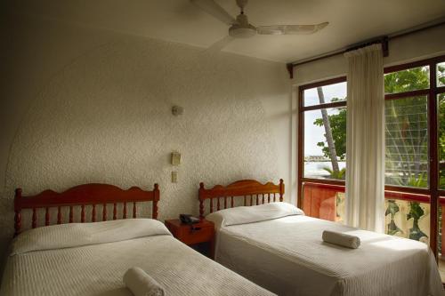 2 camas en una habitación con ventana en Rincon del Pacifico en Puerto Escondido