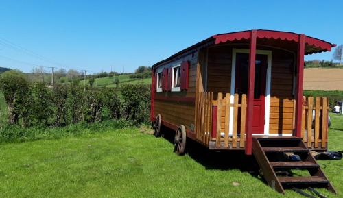 a small wooden train car sitting in a field at La roulotte au cœur de la côte d'opale in Marquise