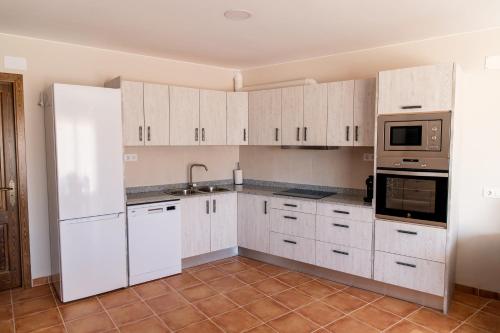 a white kitchen with white cabinets and appliances at Ca l'Apotecari in Calaceite