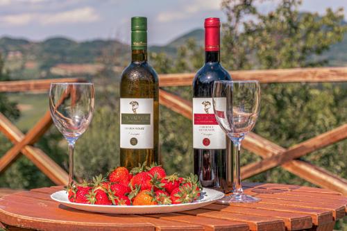two bottles of wine and a plate of strawberries on a table at Apartmani Lunija in Gornji Milanovac