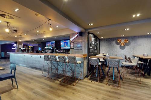 a restaurant with tables and chairs and a bar at Village Hotel Bournemouth in Bournemouth