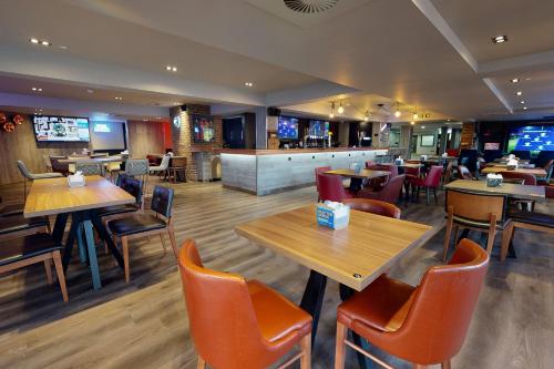 a restaurant with wooden tables and chairs and a bar at Village Hotel Bournemouth in Bournemouth
