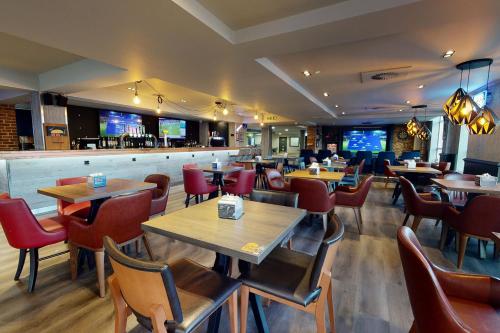 a restaurant with tables and chairs and a bar at Village Hotel Bournemouth in Bournemouth