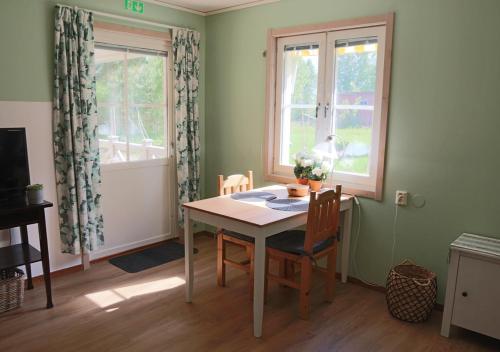 a dining room with a table and two windows at HusHotellHunge AB in Bräcke