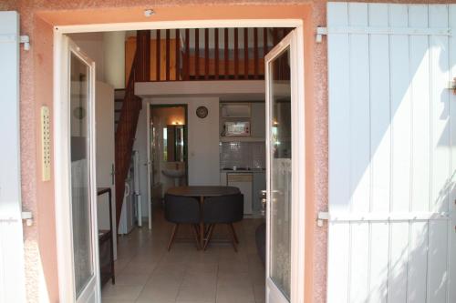 un couloir avec une porte s'ouvrant sur une cuisine avec une table dans l'établissement LE GECKO GITE, à Saint-Martin-dʼArdèche