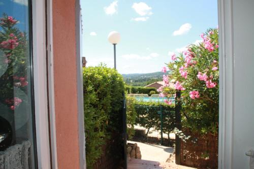 - une fenêtre donnant sur un jardin avec des fleurs roses dans l'établissement LE GECKO GITE, à Saint-Martin-dʼArdèche