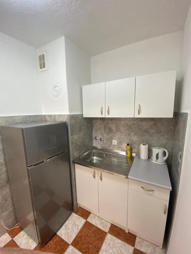 una cocina con nevera de acero inoxidable y armarios blancos en Apartman Citylux, en Bihać