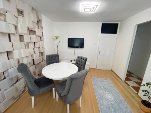 a dining room with a white table and chairs at Apartman Citylux in Bihać