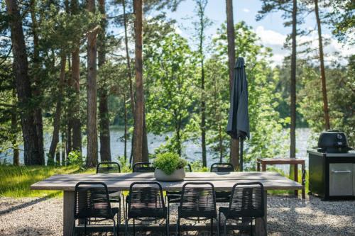 a table with chairs and an umbrella and a grill at Villa The Lake in Mindūnai