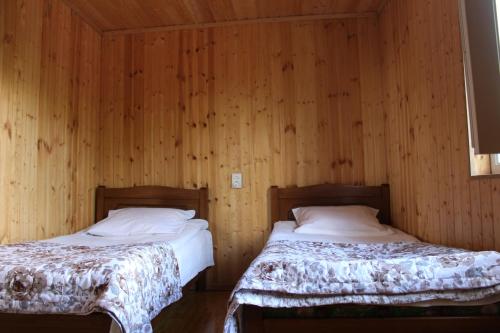 Guesthouse Marshan في أوشغولي: سريرين في غرفة بجدران خشبية