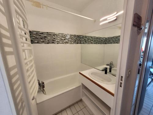 a white bathroom with a sink and a bath tub at Le Cocon de Flo, studio face à la mer au couchant in La Grande-Motte