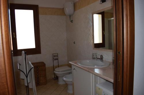 a bathroom with a sink and a toilet and a mirror at Casa rosa dei venti in Pula