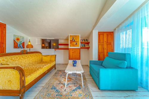 sala de estar con cama amarilla y sofá azul en Turkuaz Pansiyon, en Kalkan