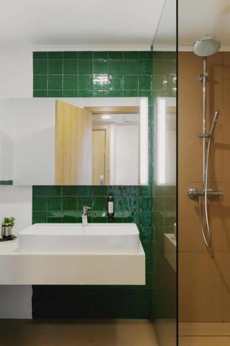 a bathroom with a white sink and green tiles at Hotel Ponta Delgada in Ponta Delgada