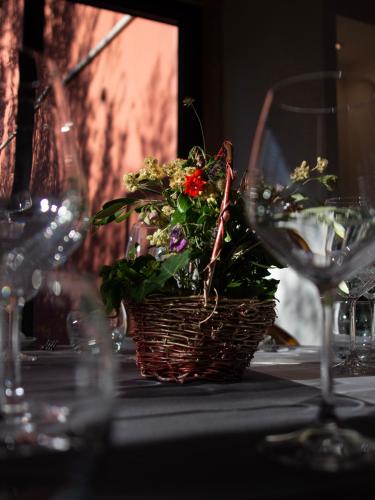 a basket of flowers on a table with wine glasses at Tropic Hôtel in Rivesaltes