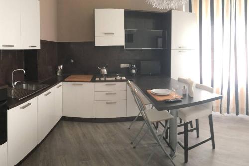 a kitchen with white cabinets and a table with chairs at Pop Apartment near Pala Alpitour in Turin
