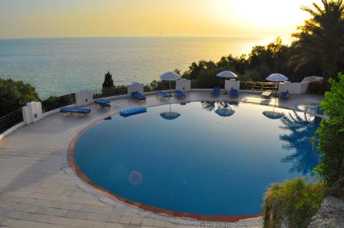 a large swimming pool with a view of the ocean at Apartments Maria with Amazing Pool - Agios Gordios Beach in Agios Gordios