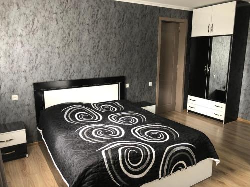 a bedroom with a bed with a black and white blanket at Katerina in Bakuriani
