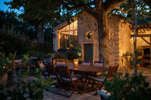 a wooden table and chairs in front of a house at Le Mas des Romarins, FAYENCE in Fayence