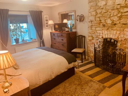 a bedroom with a bed and a stone fireplace at Molesworth Arms Pyworthy in Holsworthy