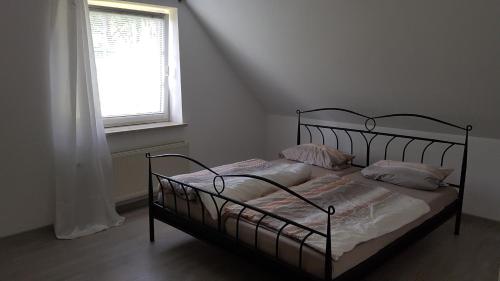 ein Schlafzimmer mit einem schwarzen Bett mit Kissen und einem Fenster in der Unterkunft Ferienhaus am Waldrand Stedden in Stedden