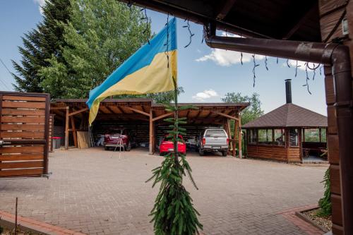 a flag hanging from a building with a parking lot at ЕкоСадиба Пан Атаман in Skhidnitsa