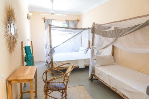 a bedroom with a bed and a chair and a table at Heart of Zanzibar Bungalows in Paje