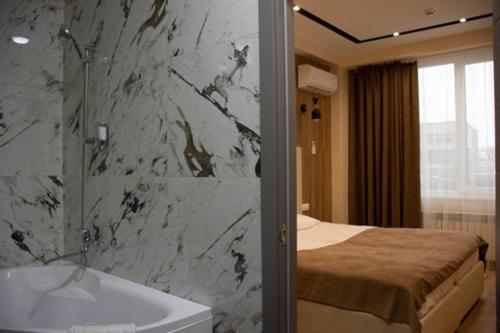 a bathroom with a sink and a bed and a tub at Lotus Hotel Chisinau in Chişinău