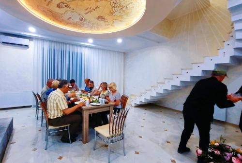 a group of people sitting at a table in a restaurant at Inaisi Hotel in Kutaisi