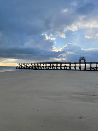 une jetée sur la plage avec un ciel nuageux dans l'établissement Beau Rivage Hôtel-Restaurant, à Luc-sur-Mer