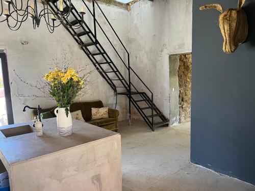 a room with a staircase and a table with flowers at Anexo Casa São Miguel the beauty of imperfection in Santarém