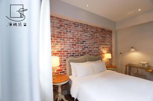 una camera con un letto bianco e un muro di mattoni di Slow Town Hotel-Reel a Taipei