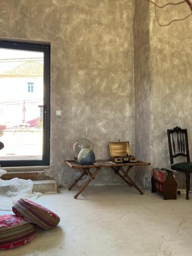 a living room with a table and a window at Anexo Casa São Miguel the beauty of imperfection in Santarém