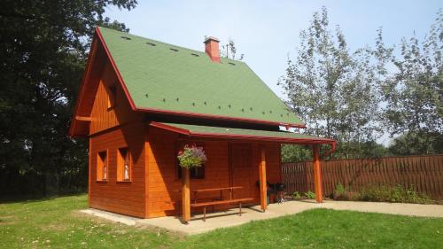 un pequeño cobertizo con un techo verde con un banco. en Chaty u rybníka Brodský, en Červený Kostelec
