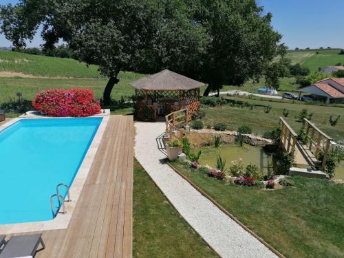 una piscina in un giardino con gazebo di Villa Lembarrat vue sur côteaux jardin et piscine privée couverte, accès PMR facilité a Calignac