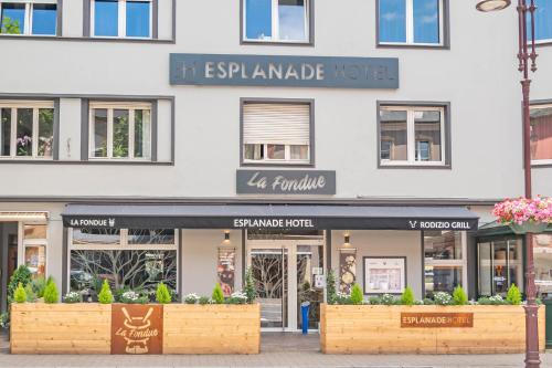 ein Geschäft vor einem weißen Gebäude mit Fenstern in der Unterkunft Esplanade Hotel in Diekirch