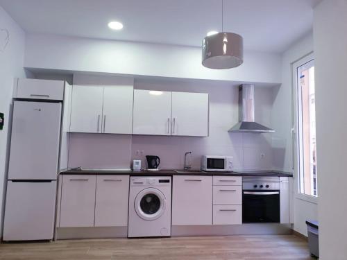 a kitchen with white cabinets and a washing machine at Premier Apartments in Valencia
