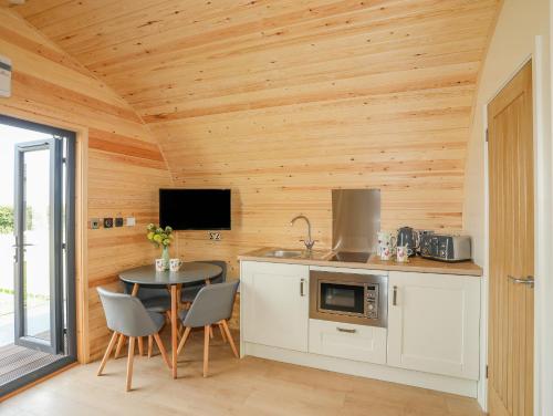 uma cozinha com paredes de madeira e uma mesa com cadeiras em Caban Cariad em Holyhead