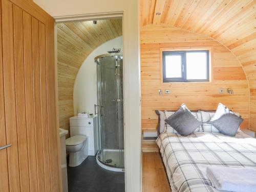 a bathroom with a shower and a bed in a room at Caban Cariad in Holyhead