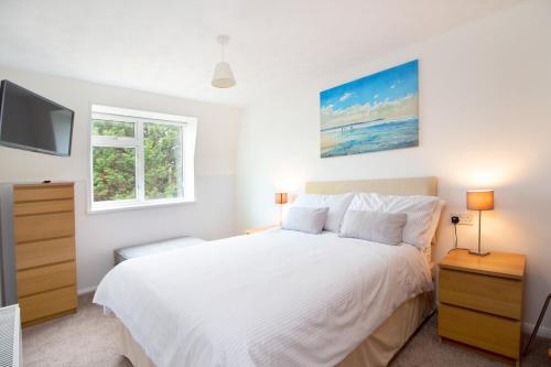 Un dormitorio con una cama blanca y un televisor. en Three Beaches Holiday Apartments - close to Goodrington beach in Paignton, en Paignton