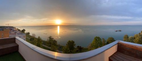 a view of the ocean from a balcony with the sunset at Galerius Harmony Penthouse in Siófok