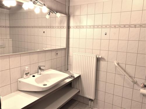 ein weißes Badezimmer mit einem Waschbecken und einem Spiegel in der Unterkunft Ferienwohnung 1 im Böhler Haubarg in Sankt Peter-Ording