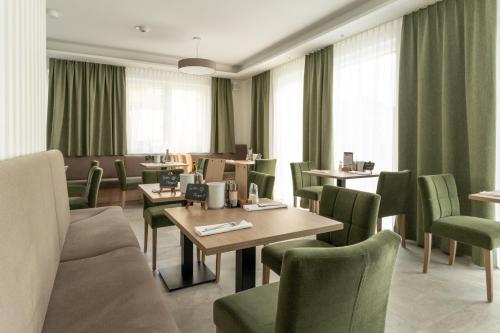 a dining room with tables and green chairs at Landhaus Bad Gleichenberg in Bad Gleichenberg