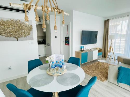 a living room with a white table and blue chairs at Wave by Baltic Home in Międzyzdroje