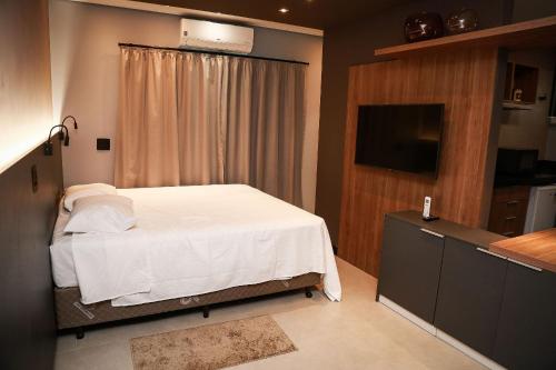 a bedroom with a white bed and a television at Globo Lar Studios in Limeira
