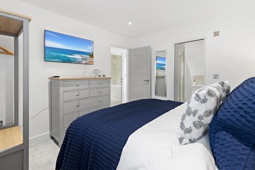 a bedroom with a blue and white bed and a television at Out to Sea, 8 Grand Banks in Teignmouth