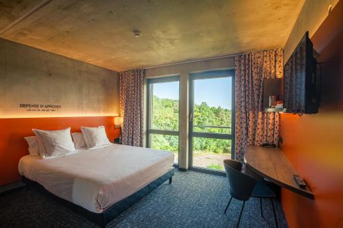 a bedroom with a bed and a desk and a window at Lorraine Hôtel Nancy Ouest - Laxou in Nancy