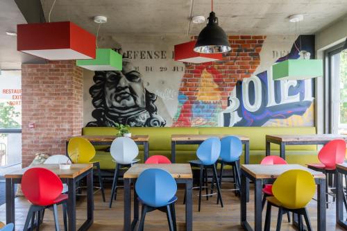 a dining room with tables and colorful chairs at Lorraine Hôtel Nancy Ouest - Laxou in Nancy