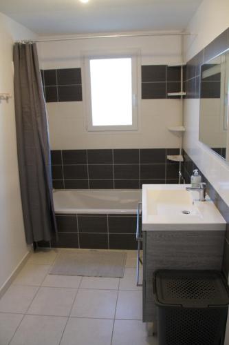 une salle de bain avec une baignoire, un lavabo et une fenêtre dans l'établissement Les lauriers de Lomagne, à Lavit